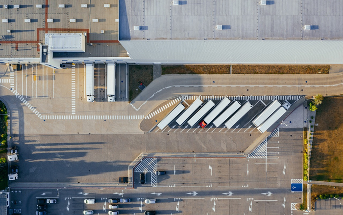 Luftaufnahme einer Lagerhalle vor der Lastwagen stehen