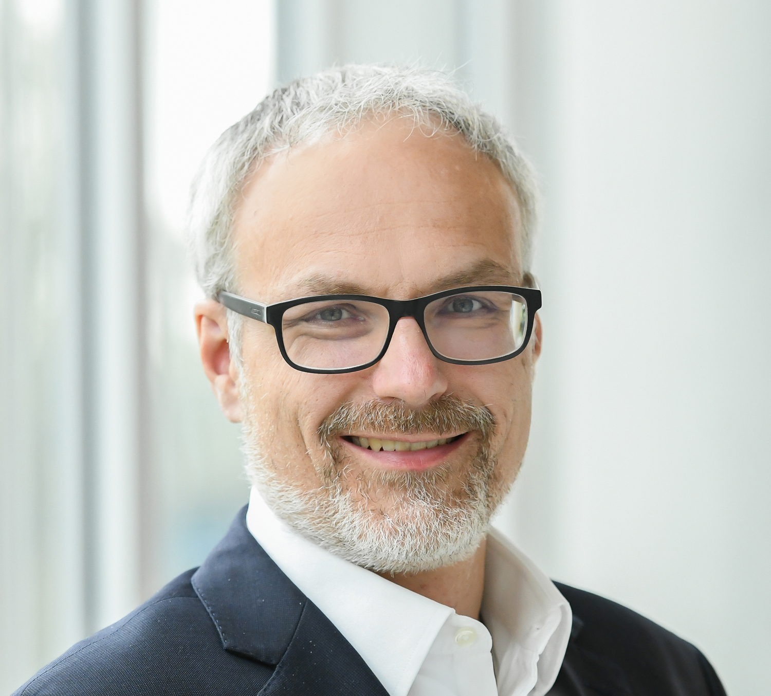 Porträt eines Manns im dunklen Anzug mit Brille