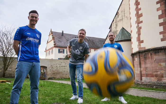 Tom Eisele, Pascal Oertel und Janik Zähringer (von links) in den Trikots ihrer jeweiligen Vereine und ein Ball der auf die Kamera zufliegt im Klostergarten in Gengenbach 