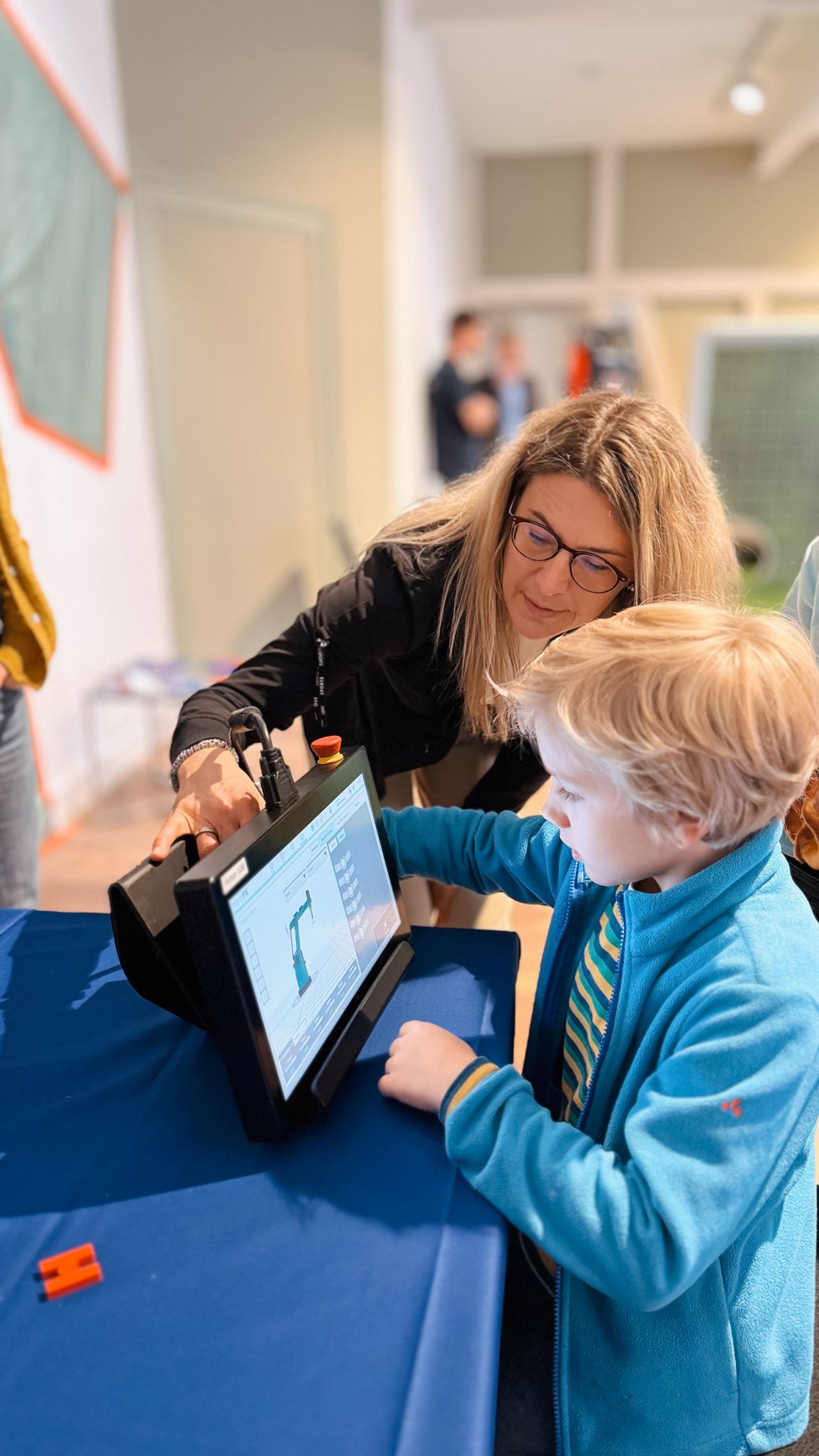 Eine Frau zeigt einem Jungen ein Tablet mit einem Roboter